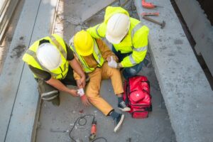 Workers in yellow vests helping injured man on construction site