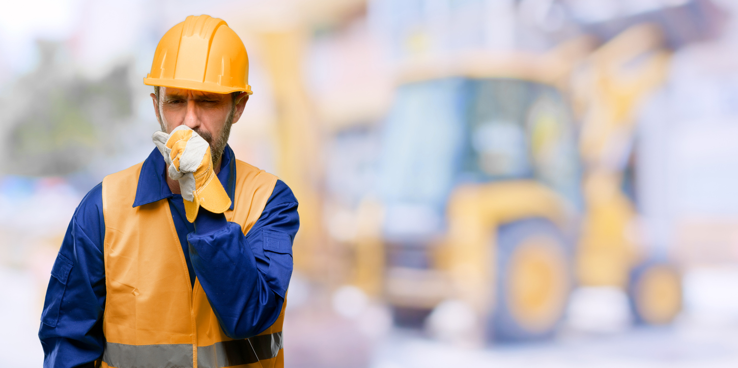 Coughing construction worker in blue shirt, yellow vest, and hard hat