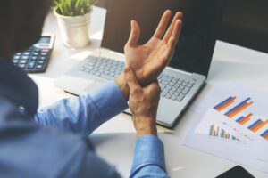 Man holding his wrist due to carpal tunnel syndrome from typing on laptop