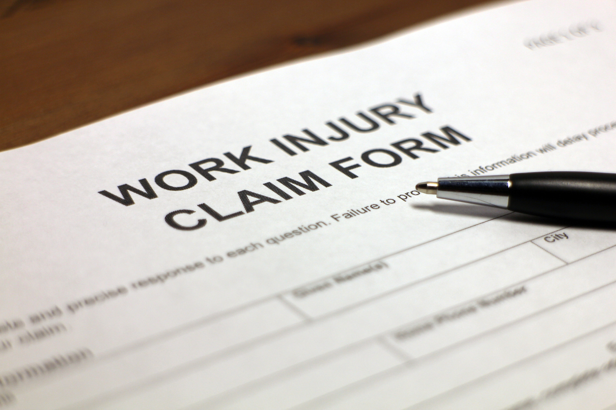 Close-up of work injury claim form with a black pen on top