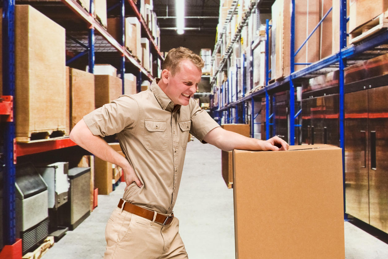 Warehouse worker holding his back and wincing in pain