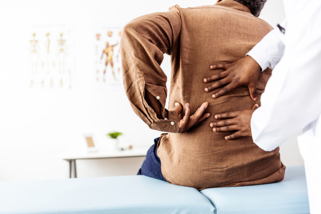 A doctor checking a man’s back injury