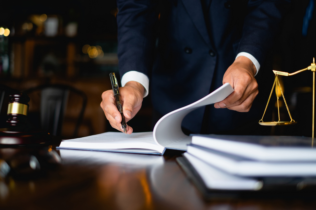 Lawyer writing on a booklet with justice scale in the foreground