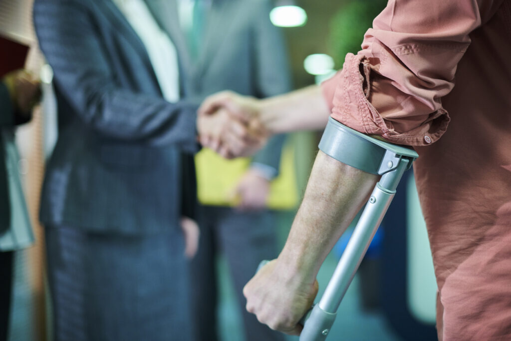Person using a crutch shakes hands with a lawyer