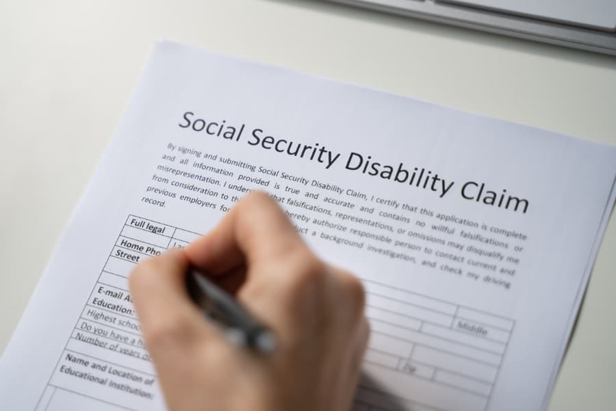 Close-up of a hand filling out a Social Security Disability claim form