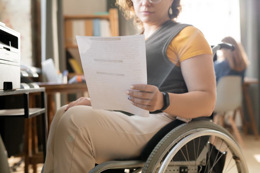 Close-up of a woman in a wheelchair holding a paper and getting ready to make copies